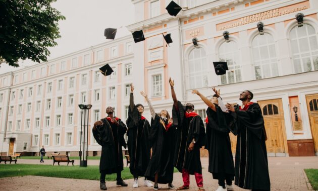 people in black academic dress standing on green grass field during daytime